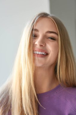 Işık arka plan üzerinde mor kazak gülümseyen kadın