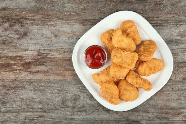 Teller mit leckeren Chicken Nuggets und Soße auf dem Tisch — Stockfoto