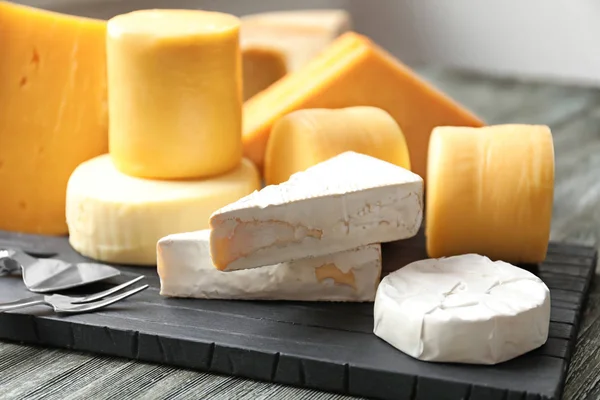 Wooden board with different kinds of delicious cheese on table — Stock Photo, Image