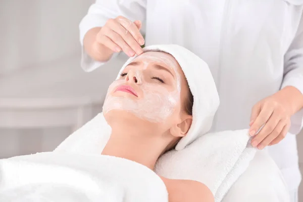 Estetista applicando crema sul viso della giovane donna nel salone spa — Foto Stock