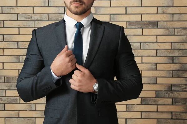 Handsome man in formal suit against brick wall, closeup — Stock Photo, Image