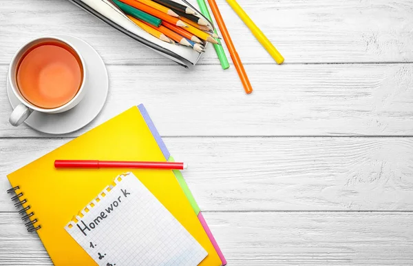 Sheet of paper with word "Homework", tea and stationery on wooden background, top view — Stock Photo, Image