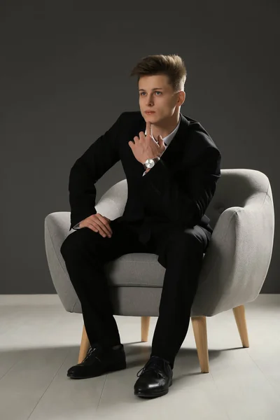 Handsome man in formal suit sitting against grey wall — Stock Photo, Image