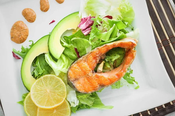 美味的煎虹鳟鱼配沙拉和调味汁在盘子上, 特写 — 图库照片
