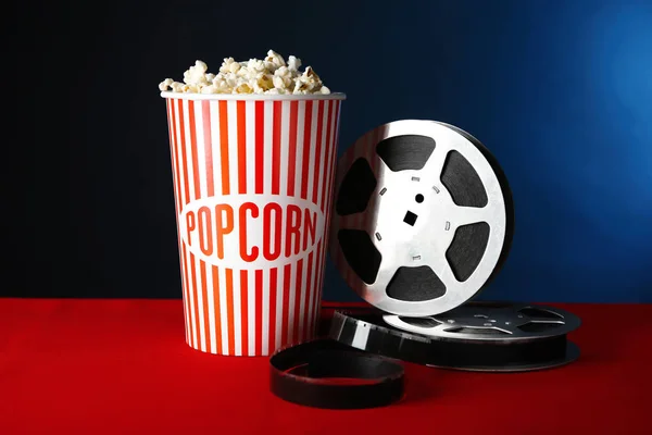 Papierowy Kubek Smaczne Popcorn Film Kołowrotek Stole Ciemnym Tle — Zdjęcie stockowe