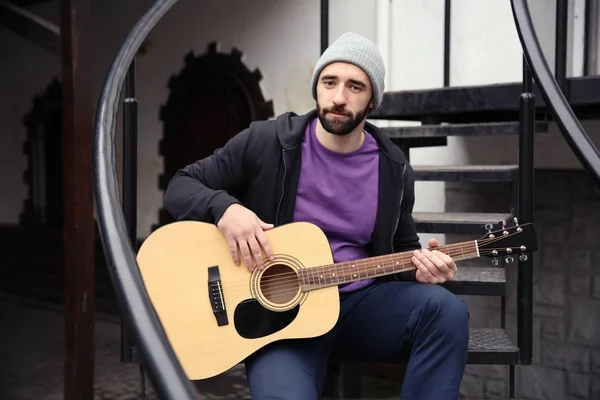 Giovane hipster uomo suonare la chitarra all'aperto — Foto Stock