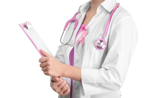 Doctor with pink ribbon on robe and clipboard against white background. Breast cancer awareness concept