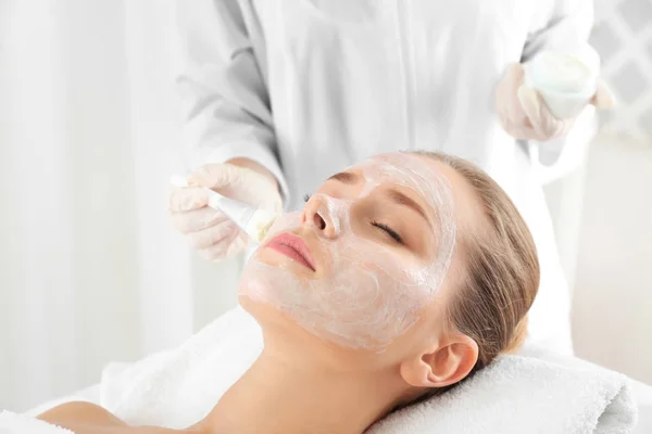 Estetista applicare maschera sul viso della giovane donna nel salone spa — Foto Stock