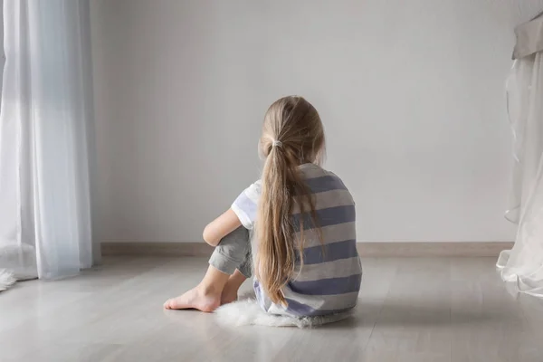 Маленькая девочка сидит на полу в комнате. Концепция аутизма — стоковое фото