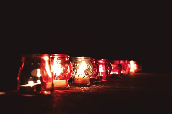 Банки с горящими свечами на каменной поверхности в темноте — стоковое фото