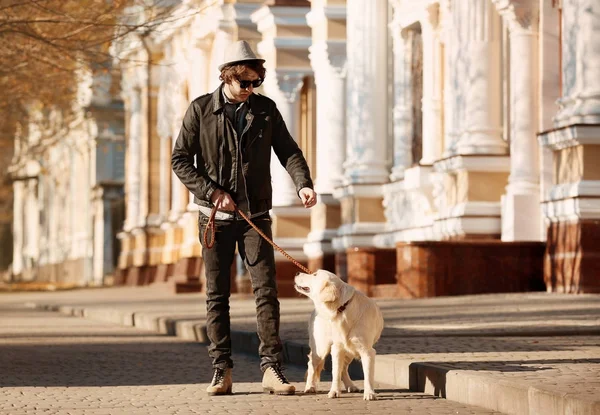 Knappe jonge hipster met hond buiten — Stockfoto