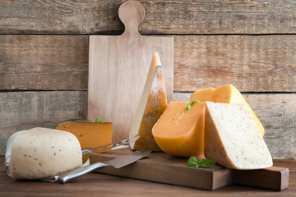 Дерев'яна дошка з різними видами смачного сиру на столі — стокове фото