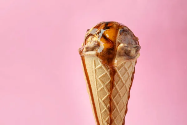 冰淇凌和焦糖调味汁在颜色背景的华夫饼锥体 — 图库照片