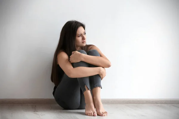 Jeune femme déprimée assise sur le sol à l'intérieur — Photo