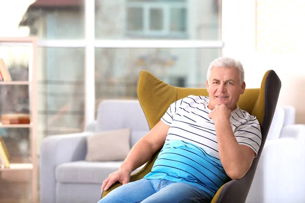 Knappe Volwassen Man Zittend Een Comfortabele Fauteuil Binnenshuis — Stockfoto