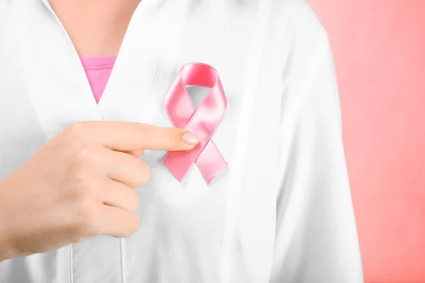 Doctor showing pink ribbon on color background. Breast cancer awareness concept — Stock Photo, Image