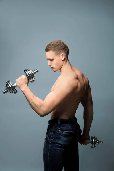 Muscoloso Giovane Bodybuilder Con Manubri Sfondo Grigio — Foto Stock