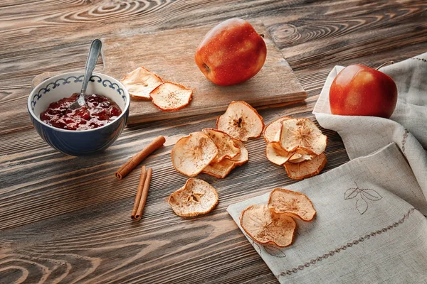 Välsmakande äpple chips och kanelstänger på träbord — Stockfoto