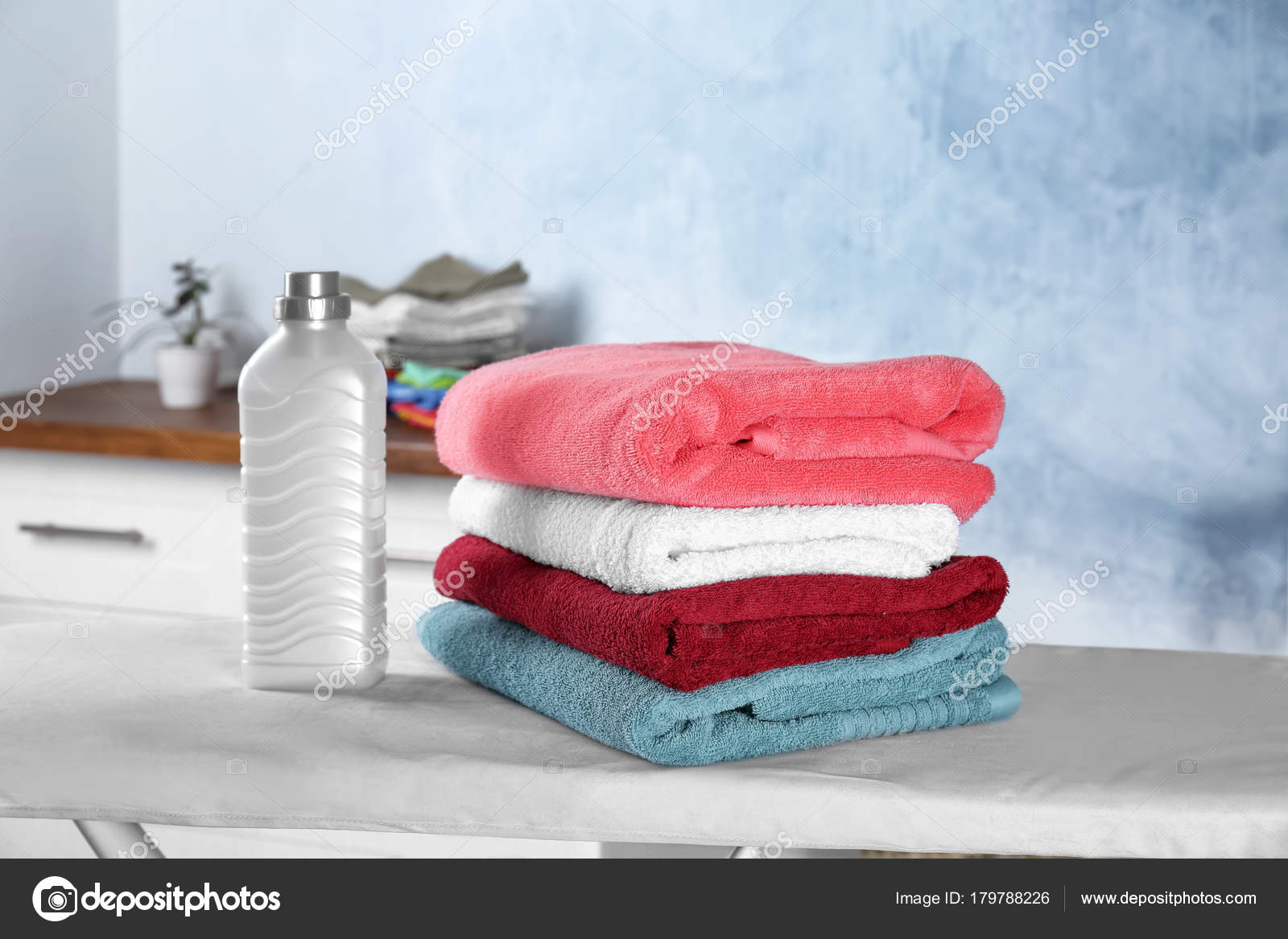 Folded towels and laundry detergent on ironing board — Stock Photo