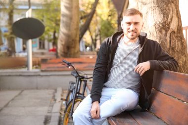 Yakışıklı genç hipster adam açık havada bankta oturan bisiklet ile