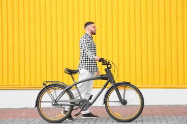 Yakışıklı genç hipster adam yakınındaki duvara açık havada bisiklet ile