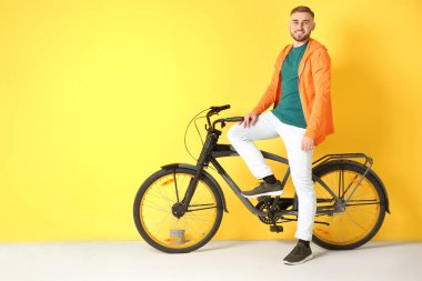 Yakışıklı genç hipster adam sarı arka plan üzerinde bisiklet ile
