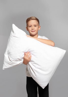 Gri arka plan üzerinde büyük yastık ile sevimli çocuk