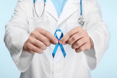 Doktor holding mavi şerit renk arka plan üzerinde. Kanser farkındalık kavramı
