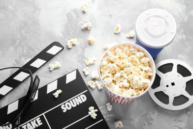 Lezzetli patlamış mısır, film makaraları ve gri arka plan üzerinde fıçı tahtası