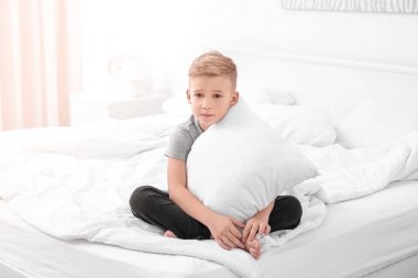 Evde yatakta beyaz yastık ile sevimli çocuk