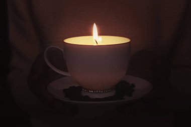 Karanlıkta, closeup mum yanan ile Kupası tutan kadın