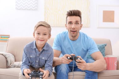 Sevimli çocuk ve babası evde video oyunu oynarken