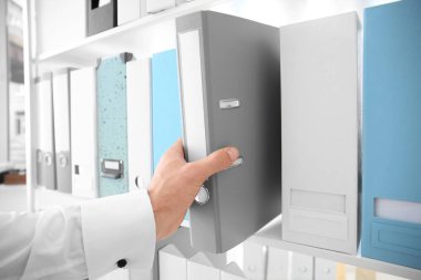 Genç adam alarak klasör raf arşiv belgeleriyle