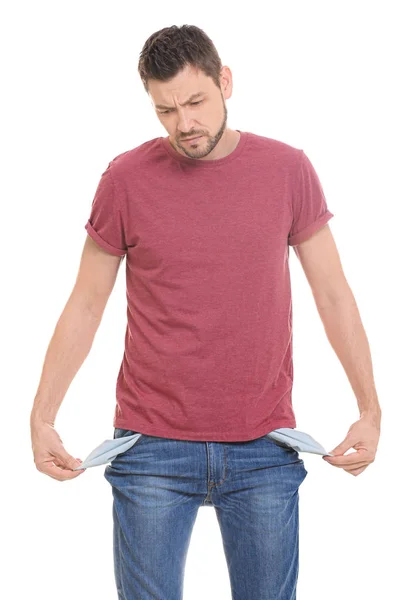 Guapo joven mostrando bolsillos vacíos sobre fondo blanco — Foto de Stock