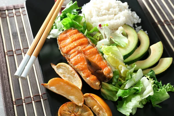 Plate with tasty rainbow trout steak and garnish on table, closeup — Stock Photo, Image