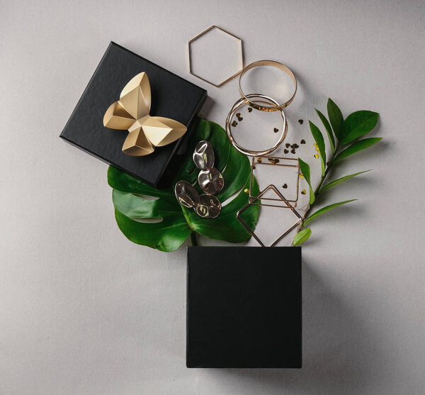 Открытая подарочная коробка и золотые аксессуары на светлом фоне, вид сверху
