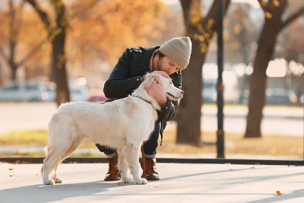 Bello giovane hipster con cane all'aperto — Foto Stock