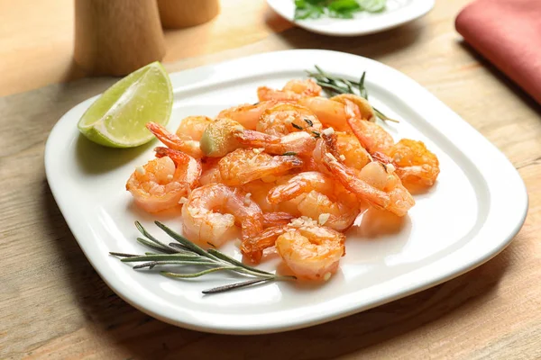 Prato com deliciosos camarões fritos e alho na mesa — Fotografia de Stock