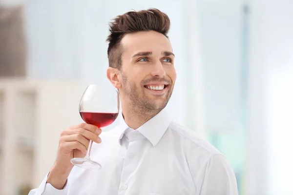 Bello giovane che beve vino rosso in casa — Foto Stock