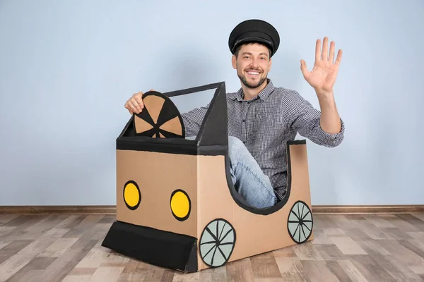 Νέος άνθρωπος ονειρεύεστε δική auto παίζοντας με αυτοκίνητο από χαρτόνι σε εσωτερικούς χώρους — Φωτογραφία Αρχείου
