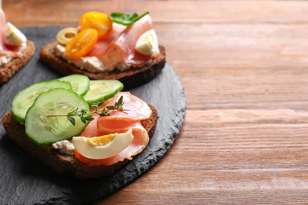 Assiette d'ardoise avec de savoureux bruschettas frais sur la table — Photo