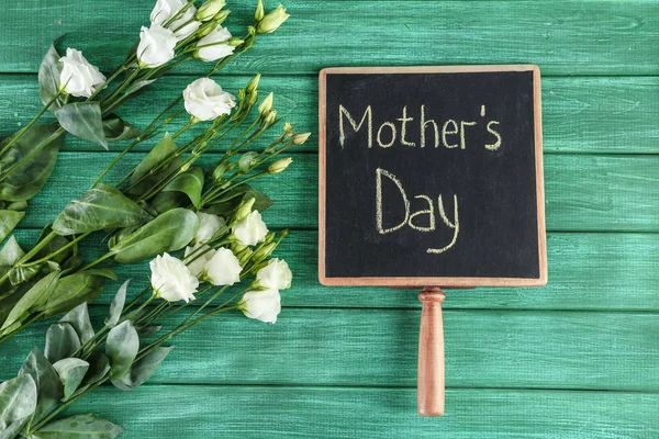 Kreidetafel mit dem Satz Muttertag und Blumen auf Holzgrund — Stockfoto