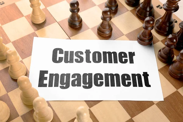 Sheet of paper with text CUSTOMER ENGAGEMENT and pieces on chessboard