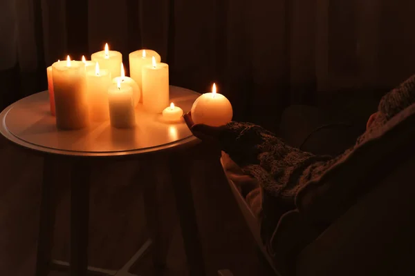 Žena držící hořící svíčku u stolu v temné místnosti — Stock fotografie