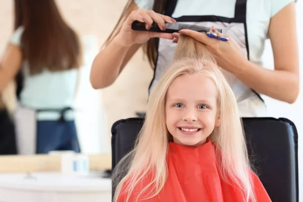 Женщина парикмахер работает с маленькой девочкой в салоне, крупным планом — стоковое фото