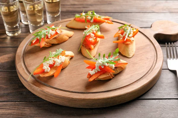 Placa de madeira com saborosas bruschettas frescas na mesa — Fotografia de Stock