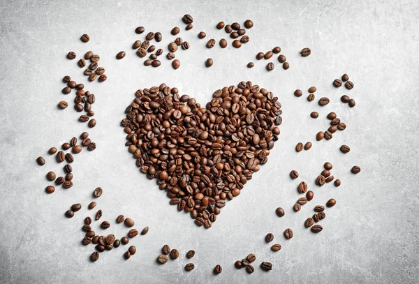 Kahve çekirdekleri ışık arka plan üzerinde kalp yapılmış — Stok fotoğraf