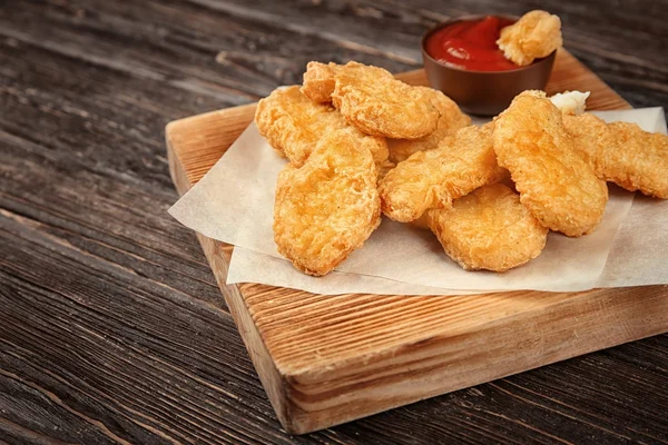 Deska z tasty chicken nuggets i sosem na stole — Zdjęcie stockowe