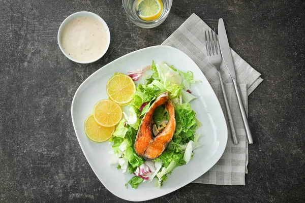 Heerlijk gebakken regenboogforel met salade en saus op grijze achtergrond, bovenaanzicht — Stockfoto