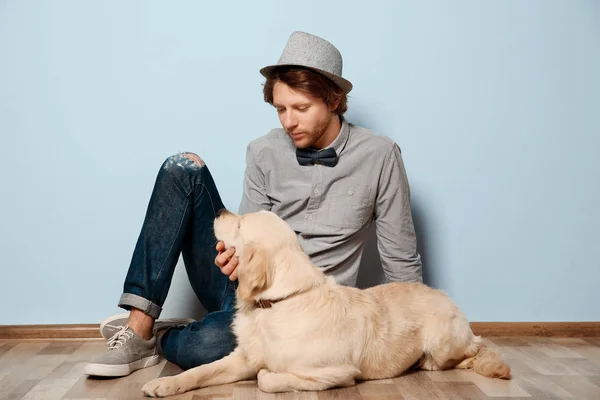 Handsome young hipster with dog indoors — Stock Photo, Image